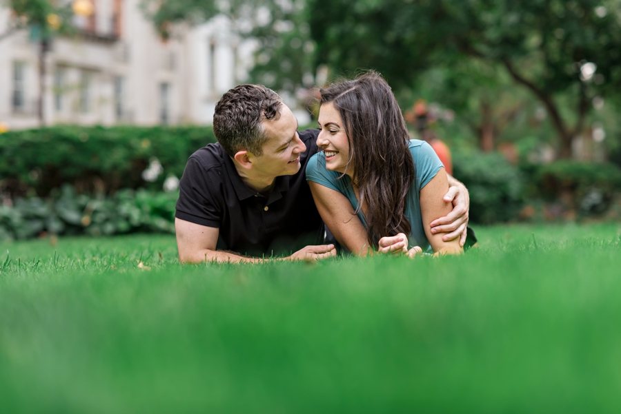 A man puts his arm around his girlfriend while they lay in the grass.
